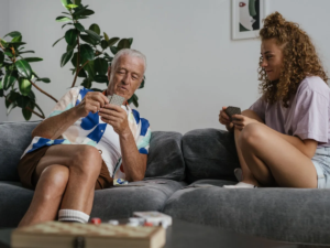 Older man and young woman playing cards together on a sofa at home