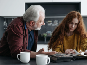 Older man and young woman looking through a photo album together over tea