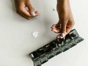 Hands placing tablets into a weekly pill organiser